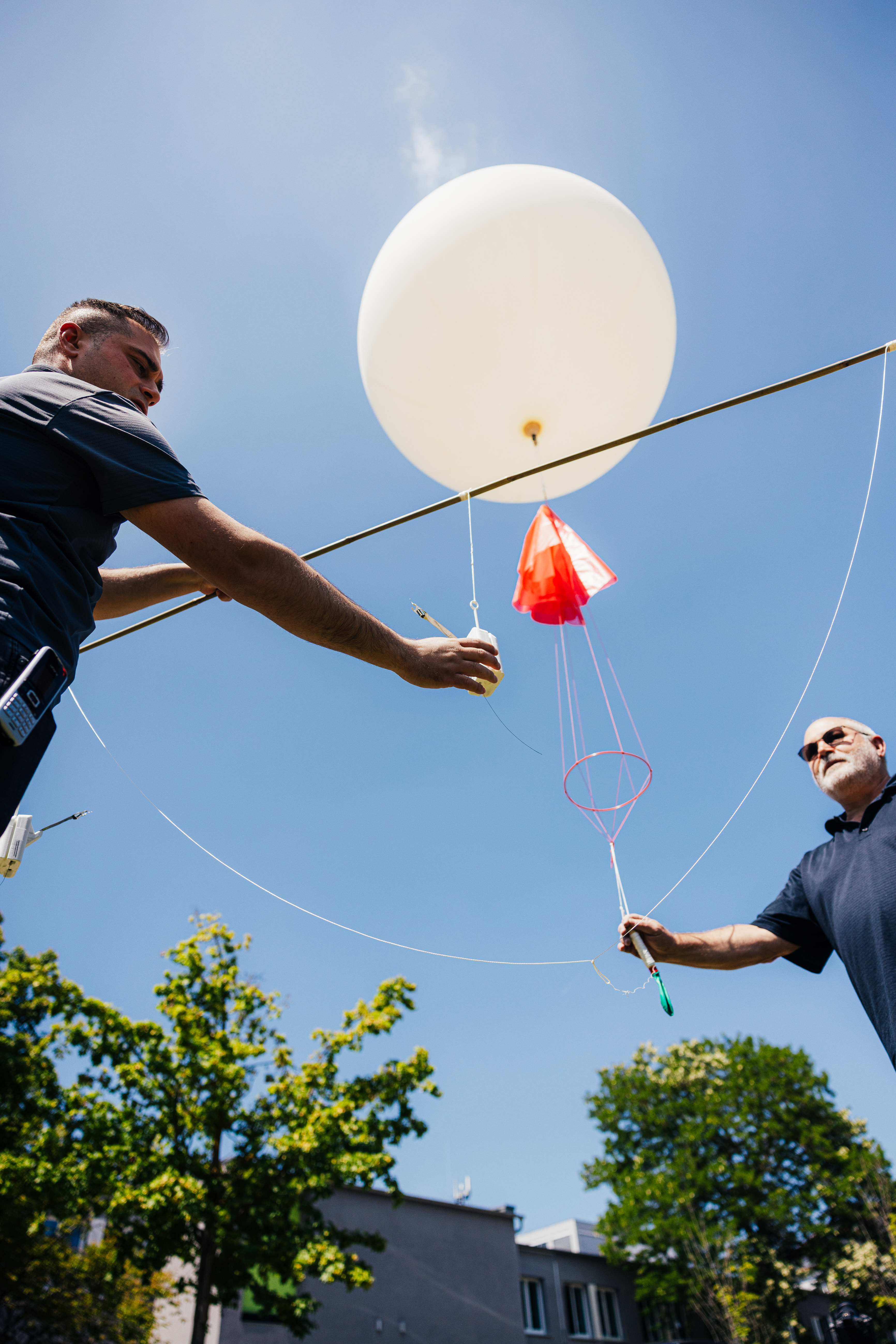 The image shows a white balloon with a connected radiosonde.